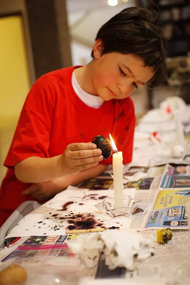 Boy decorating egg with candle Student decorating egg and curating with candle flame